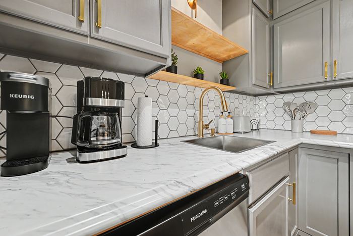 Kitchen counter in Apartment 3N with coffee makers, marble countertop, and brass faucet