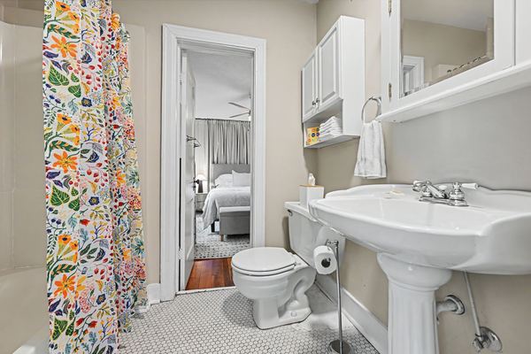 Bathroom in Apartment 3S with floral shower curtain and pedestal sink