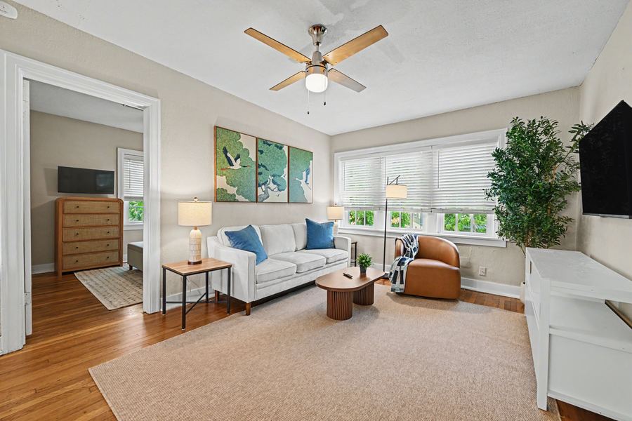 Living room of Apartment 3S with sofa, leather swivel chair, and crane triptych artwork