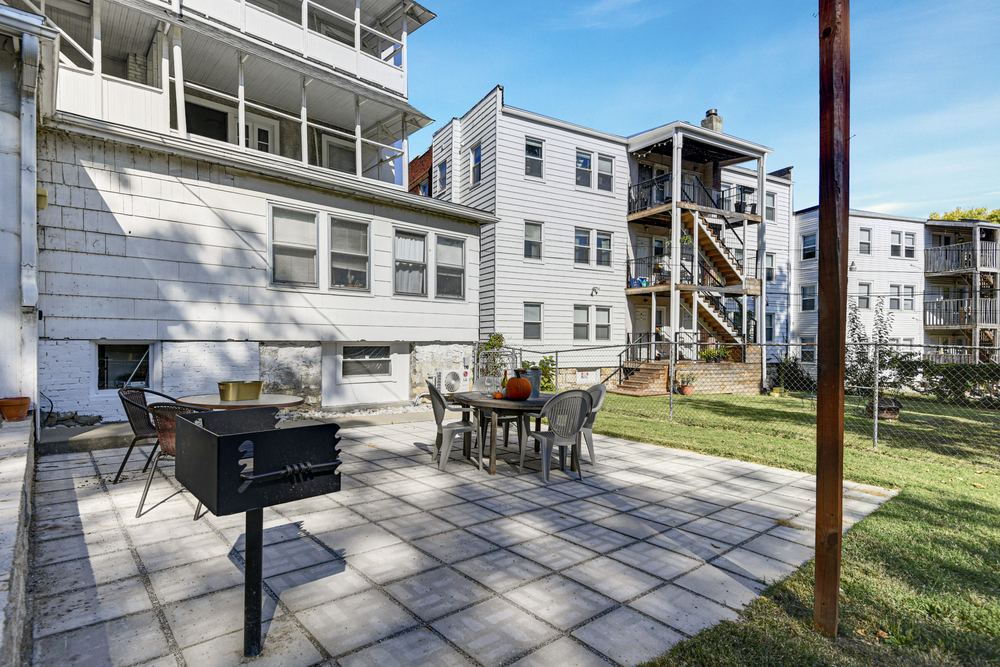 Fenced backyard with paver patio, dining table, and charcoal grill